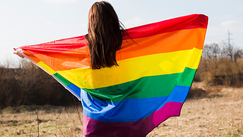 woman holding pride flag behind her back